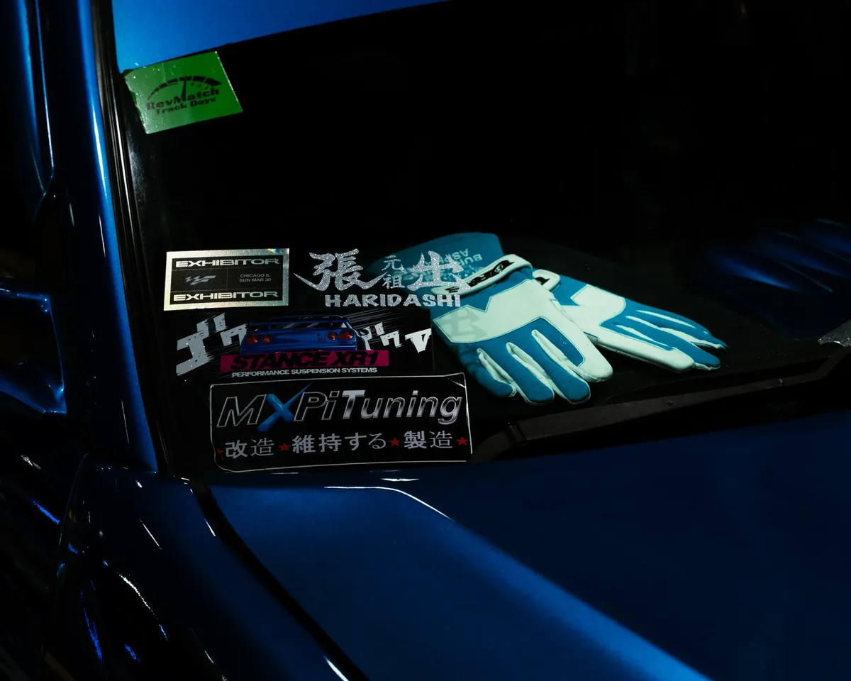 Track day gloves and stickers on a blue dashboard